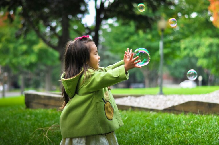 A happy child playing on a lush green lawn, surrounded by colorful flowers and a safe, toxin-free environment. The lawn is perfect for kids to run, play, and enjoy outdoor activities.